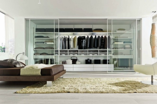 This particular closet space is installed inside the wall and includes glass door panels that slide into the sides of the wall, which expands bedroom space. The different size shelves and compartments are versatile for various types of wardrobe.