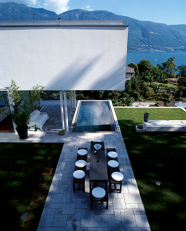 The east wing of the building extends as an overhang above dark granite tiled pool with shimmering water and a spectacular view of the Swiss Alps and deep blue waters of Lake Maggiore. The overhanging roof of the villa also protects it from strong sunlight.