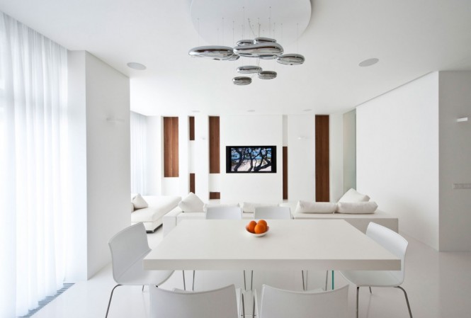 To continue the laid back luxurious style from floor to ceiling, the over dining table pendant light fixture is futuristic yet understated, visually interesting but not demanding of attention or causing distraction. The dining table itself blends in simply with its surroundings in a white on white setup.