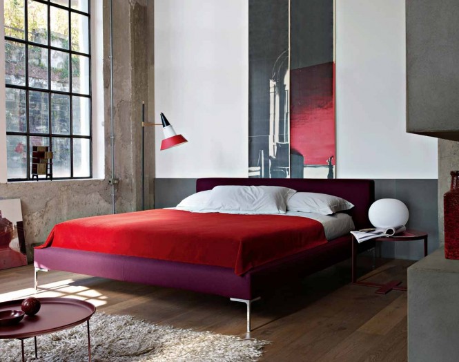 In the bedroom, a clash of purple bedstead and red bedcovers create a passionate palette to warm the cold concrete walls.