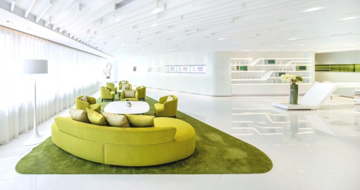 The ceiling holds a series of white beams of varying lengths to create architectural lines above a lime-on-lime reception area that has been designed to emphasize the young and rejuvenated brand essence. The fabric sofas have been designed with soft, rounded edges to appear inviting and welcoming to customers.