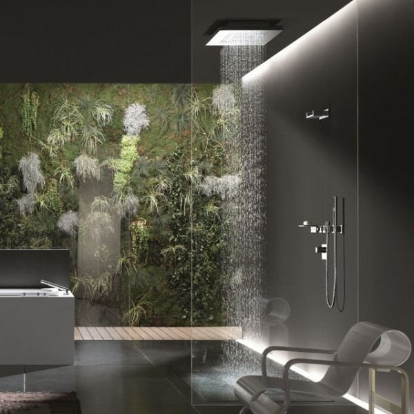 A living wall filled with foliage, moss and fern fronds provides a natural focal point in this modern bathroom. A rainshower fixture is lighted dramatically from above.