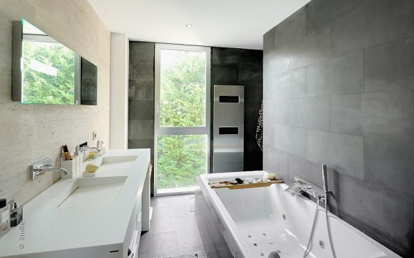 Huge slate tiles give the bathroom scheme a modern edge, along with twin minimalistic basins and a streamlined towel heater.