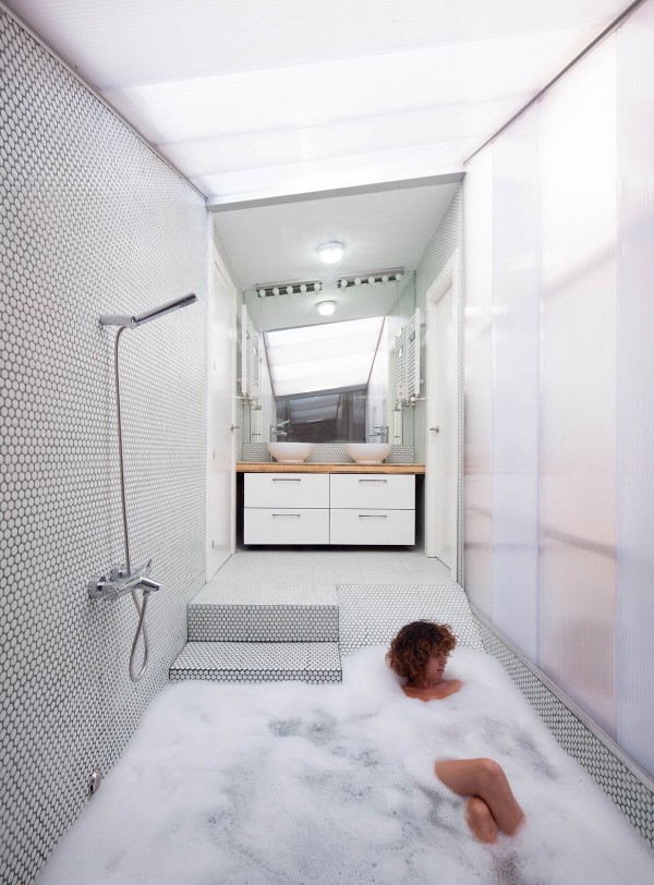 A swathe of mosaic tiles cover the shower area over and around this sunken bath tub.