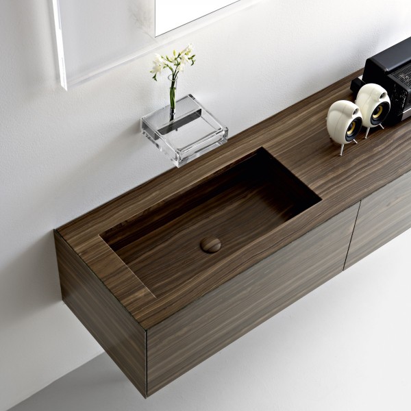 This block walnut vanity unit with integrated basin keeps a contemporary scheme looking streamlined. The wall mounted faucet takes the form of a neat glass shelf, complete with a place for a small floral display.