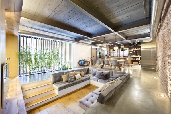 The interior embraces a loft feel with exposed brick faces, rustic ceiling beams, industrial ducting, and concrete floors. However, the stark backdrop almost fades away with the introduction of warming woods and plush furniture, amongst the homes pretty landscaped heart.