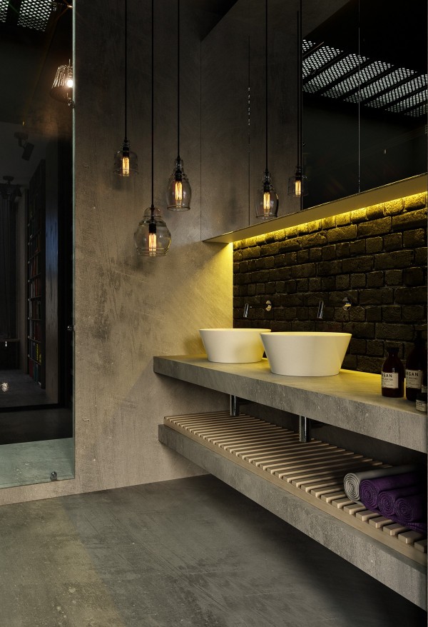 Black-painted brick and a full-length mirror give the bathroom a moody and sophisticated appeal. Yellow indirect light ties back to the home's distinctive color theme and contributes to the relaxing atmosphere.