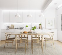 White walls and cabinetry allow the dining arrangement to stand out with emphasis, the natural wood of the simple table and iconic Wishbone chairs serving as a strong contrast to the minimalistic materials used throughout.