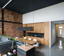 This space blends the industrial with the organic seamlessly, and you can see that here in the open kitchen living space. The brick wall is quintessential for an industrial space, but mixed with the warm wood cabinets and the scattered plants, this space is infused with a bit of nature.