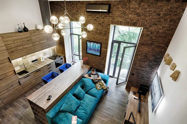 A 49-metres-squared loft in Kiev by Ivan Yunakov (http://yunakovdesign.com) also uses signature shades to create harmony in cosy spaces. High-ceilinged brick and panelled wood fixtures afford the height for long-lined doors, which are stretched horizontally by similar-shaped benches. A turquoise couch with electric blue suede single seats offer seats to look at bauble lighting, the only rounded fixture in the room.