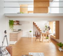 A striking feature, the wooden block staircase is the first introduction to this bicultural home. Using three types of wood for shelving, tables and floors, the living space retains simplicity with clean, simple lines, retaining interest through muted-pattern throws and rugs. Potted and hanging plants add life.