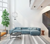 The first sight of the interior-designed living room is a unified example of how to bring several themes together in one space. Complementary orange and sky-blue tones are back-dropped by tones of living green, while a dark wood staircase adds grounding to the room. A lightly-patterned rug adds conversation between the elements. Round bauble lighting mimics the lines of the table.