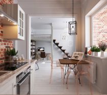 From the kitchen, earthier tones come into play. Scrumptious brick reds expose themselves in the kitchen, with wooden benches and a table to settle them. Table chairs in light brown plastic add modernity, while a white-framed enclave invites from the more-muted living room.