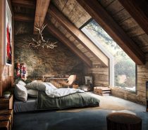 This rustic attic bedroom is striking. The chandelier made from antlers is lit up by the natural light let in by the large window. Wooden walls and a wood burning fireplace make this space so cozy.